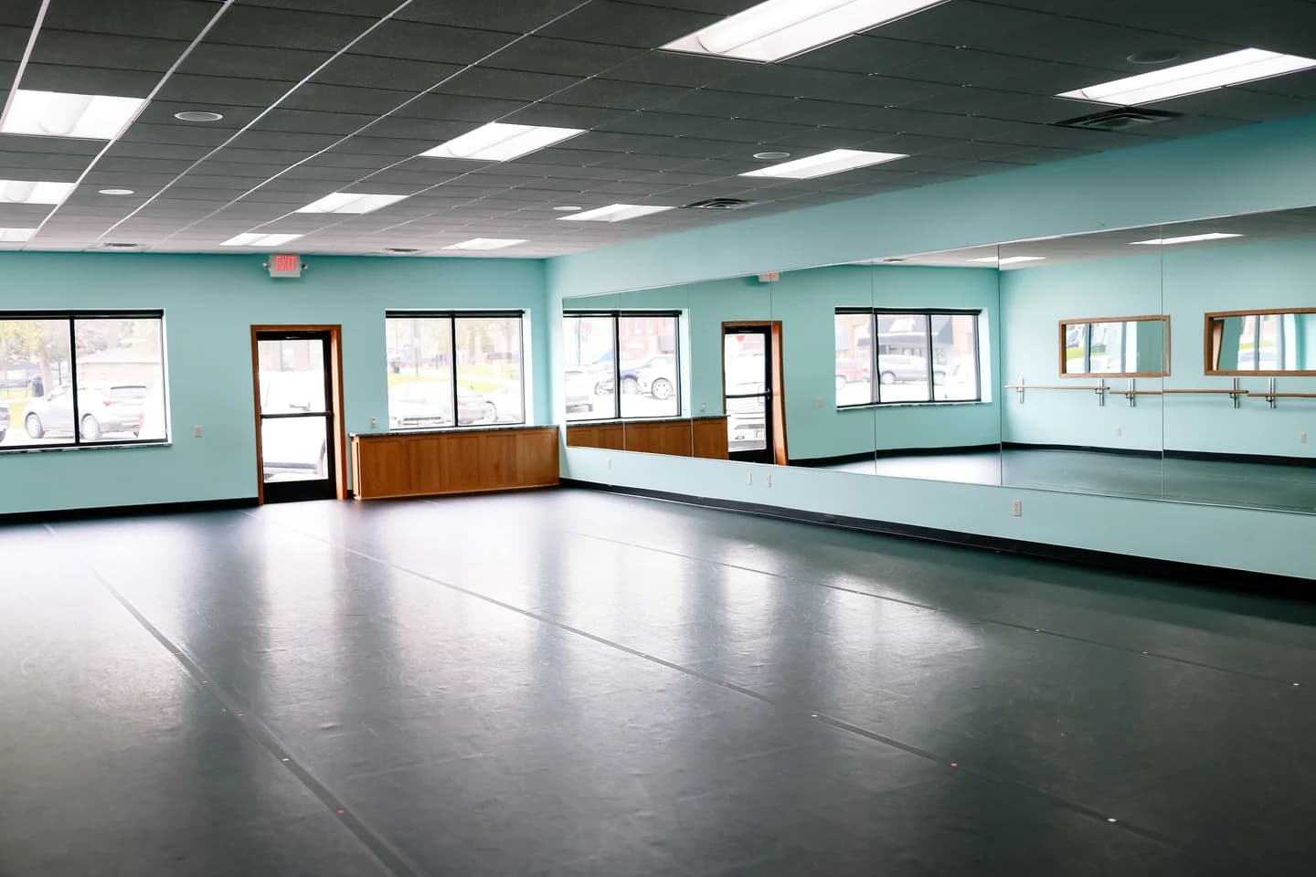 Melinda's Dance Studio Front Main Studio with black flooring, teal walls, mirrors, and barres